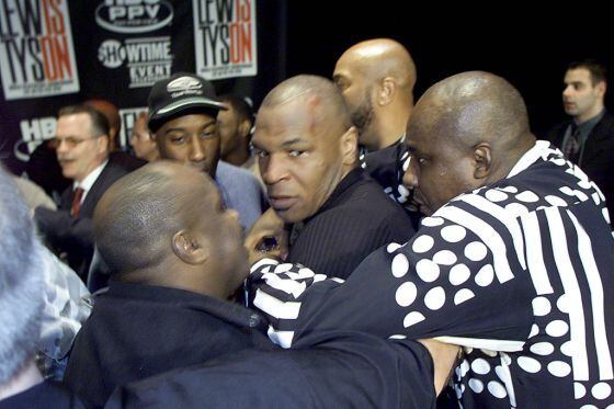 Mike Tyson (en el centro) es retirado tras comenzarse una pelea con Lennox Lewis en Nueva York en 2002.