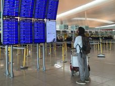 Un pasajero mira los paneles informativos hoy en la T-1 del aeropuerto de El Prat.