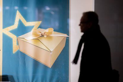 A man passes a shop window with a picture of a Christmas present on the street.