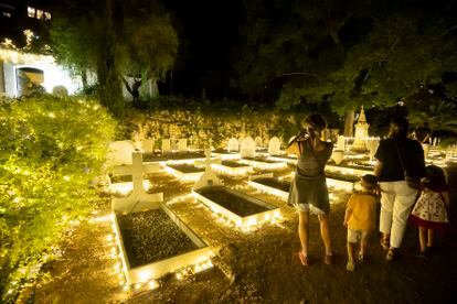 Una familia observa las tumbas iluminadas del cementerio inglés de Málaga.
