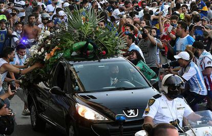 Aficionados se apiñan junto al coche fúnebre que transportaba el féretro de Diego Armando Maradona a la salida de la Casa Rosada.