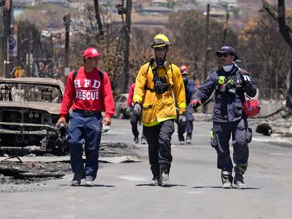 Members of a search-and-rescue team walk along a street, Saturday, Aug. 12, 2023, in Lahaina, Hawaii, following heavy damage caused by wildfire. (AP Photo/Rick Bowmer)