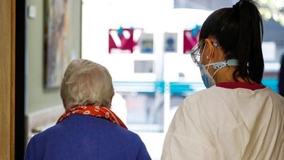 Una trabajadora de una residencia de mayores en Madrid ayuda a una paciente.