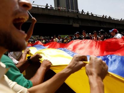 Un grupo de protestantes en contra de Nicolás Maduro sostienen la bandera de Venezuela.