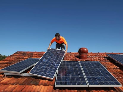 Un operario coloca paneles solares sobre un tejado.