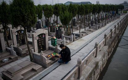 Un joven reza frente a una lápida en el 'Día de barrer tumbas' o 'Qingming' en un cementerio público de Shangai, (China).