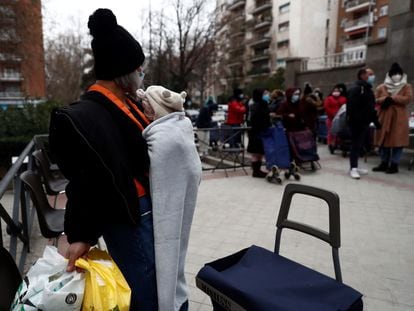 Varias personas esperan su turno para recibir alimentos, este jueves, en la plaza de San Amaro en Madrid.