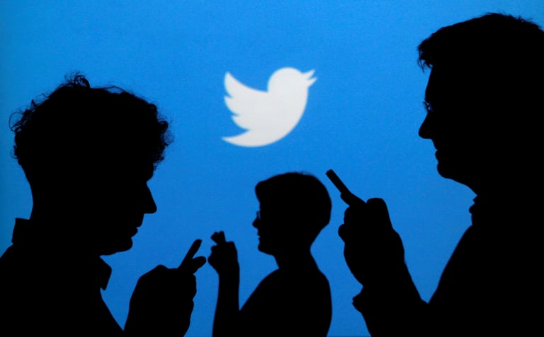 El logotipo de Twitter y algunas personas con sus móviles.