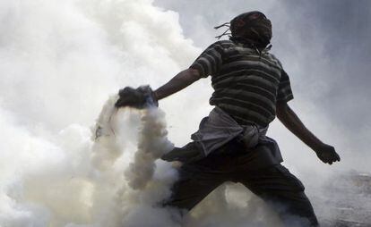 Un manifestante lanza gas lacrimógeno en Tahrir.