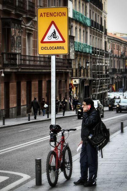 Un hombre que habitualmente circula en bici por Madrid, ata su Mountanbike de 300 euros, a la señal del ciclocarril. Atar la bicicleta a una señal está prohibido