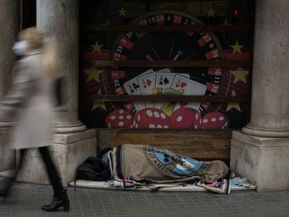 Una persona sin hogar duerme en la entrada de un casino en Barcelona.