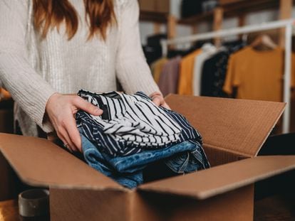 A millennial woman is preparing the shipment of some clothes in her new online shop. She's the owner of an online thrift store. New small business concept.