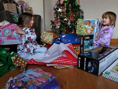 Dos niñas abren sus regalos, durante la mañana de un día de Reyes, en Madrid.