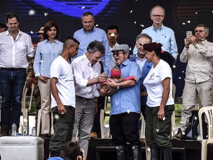 Una pareja de guerrilleros entrega a su bebé a Rodrigo Londoño, líder de las FARC, y al presidente colombiano Juan Manuel Santos, durante el acto del final de las armas en Mesetas (Colombia).