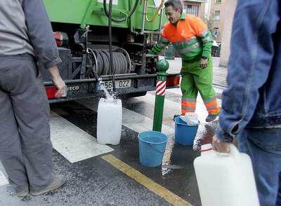 Empleados municipales servían agua de uno de los camiones-aljibe a vecinos de Rekalde.