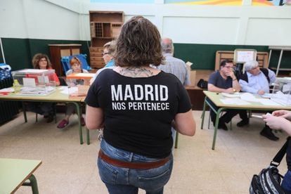 Una mujer se dispone a introducir sus votos en las urnas durante la jornada electoral, en el colegio público Costa Rica del barrio de Aluche, en Madrid.