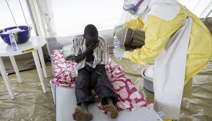 Un médico da de beber a un enfermo de ébola en el centro de aislamiento de Kailahun (Sierra Leona).