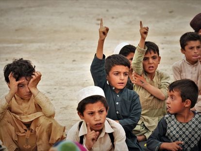 Varios niños responden a la petición del profesor de participar durante una clase al aire libre en un pueblo sin colegio de la provincia afgana de Kandahar.