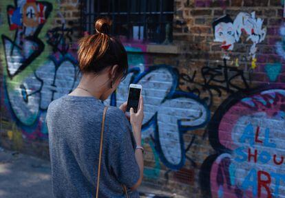 Una joven fotografía un grafiti en Brick Lane, Londres.