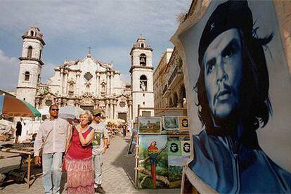 Unos turistas pasan junto a un cartel del Che Guevara en un puesto de la plaza de la Catedral, en La Habana.