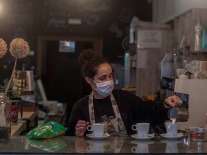 Una camarera sirve cafés en un bar.