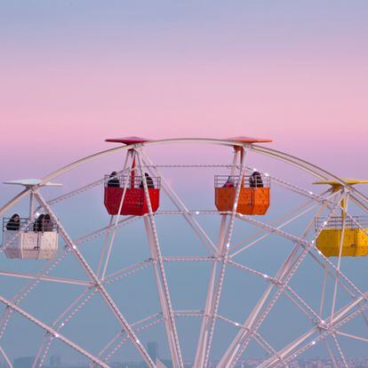 View of the colorful ferris wheel in the Tibidabo amusement park with families and couple spending the week end on the attractions.