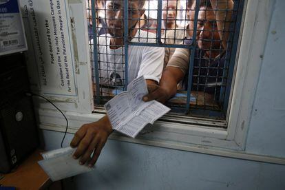 Los palestinos se agolpan en la ventana de un centro de distribución de alimentos de la ONU para recibir ayuda en el campo de refugiados de Shati en la ciudad de Gaza.