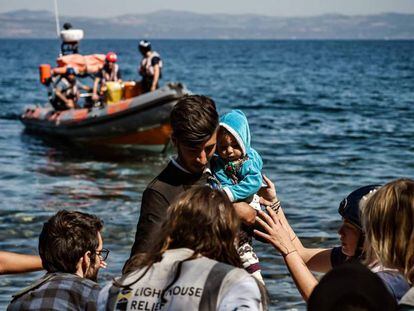 Un migrante con su bebé, ayudado a su llegada de la isla griega de Lesbos, el pasado lunes.