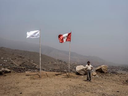 Un habitante del distrito de Carabayllo, de Lima, hace guardia frente a la bandera blanca y la de Perú.