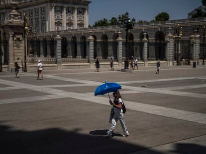 A woman shelters from sun with an umbrella in front of the Royal Palace during a hot a sunny day in Madrid, Spain, Monday, July 18, 2022. (AP Photo/Manu Fernandez)