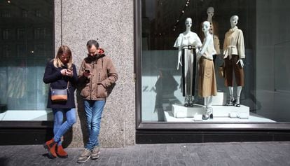 Una pareja consulta en el móvil ante un escaparate, en Madrid.