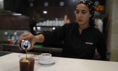 Una camarera sirve un refresco en la barra de un bar.