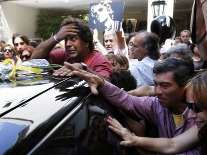 Aficionados del fallecido m&uacute;sico argentino Luis Alberto Spinetta siguen el coche con su at&aacute;ud, tras su funeral.