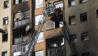 Los bomberos evacuan a vecinos del edifico quemado en Badalona.