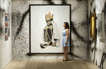 Una empleada de Sotheby's posa al lado de la obra de arte 'Burger King', realizada en 2006 por Banksy.