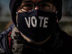 Un votante con una máscara en la que se puede leer "Vota" hace cola en un centro de votación en el Parque Nacional, en Washington, DC. Las de este martes serán unas elecciones complejas. El alto número de votos recibidos antes de la jornada electoral y las leyes de cada uno de los 50 Estados hacen impredecible definir el desarrollo de la noche.