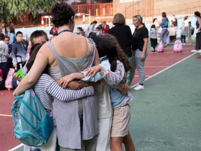Una maestra se abraza a sus alumnas en el patio de un colegio de Madrid en el primer día de clases 2023-2024.