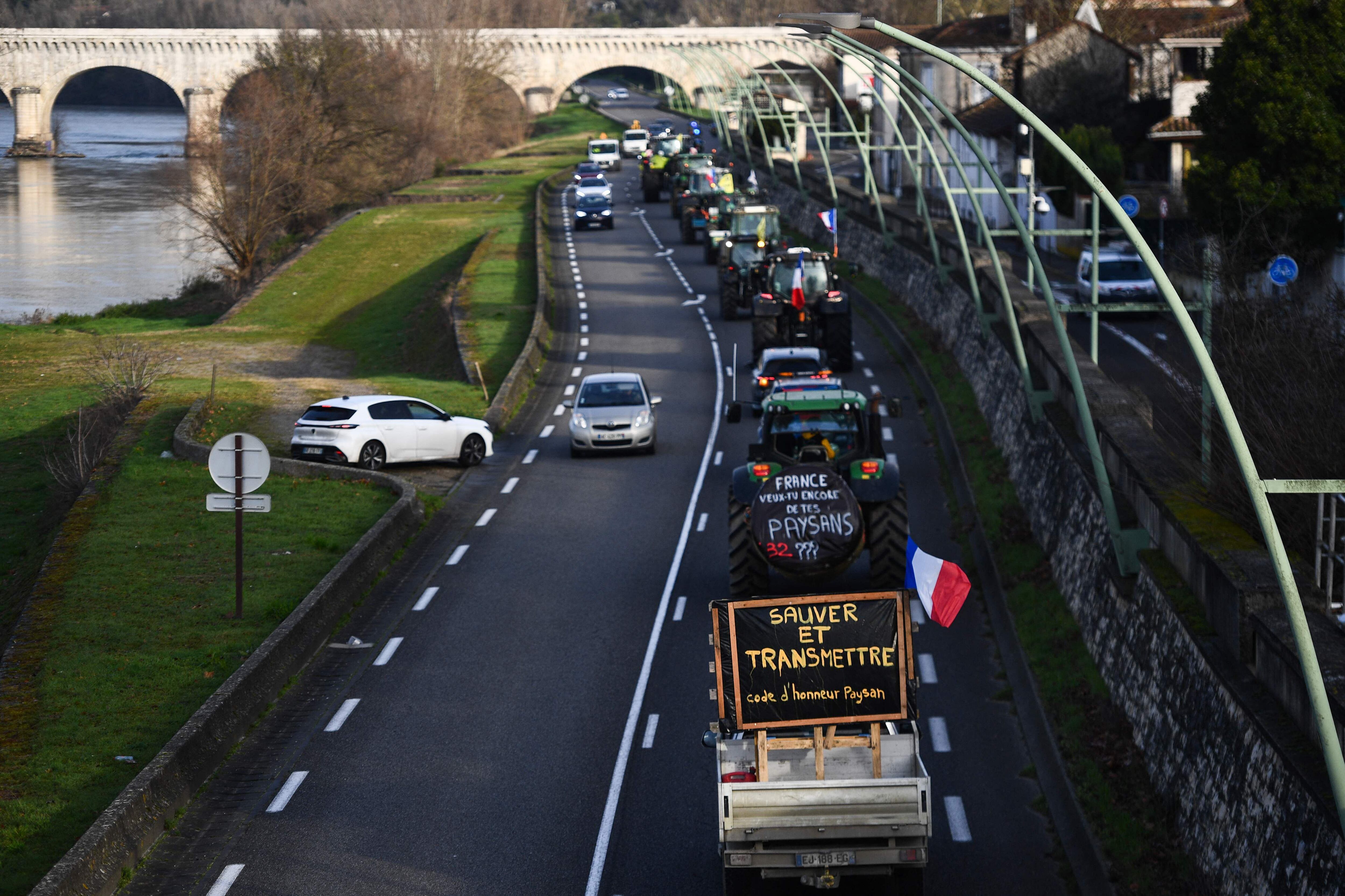 Los agricultores franceses marchan con sus tractores por la carretera. Uno de ellos (abajo) porta un cartel que dice 