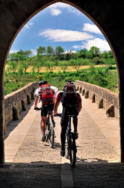 Dos ciclistas en el puente rom&aacute;nico de Puente la Reina, en el Camino de Santiago a su paso por Navarra. 