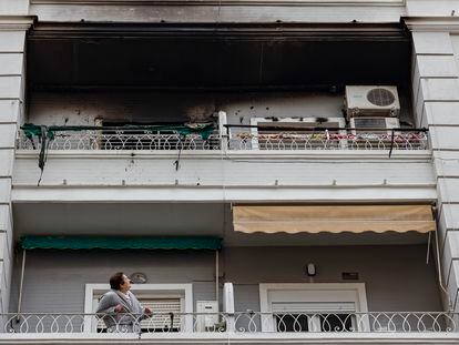 Una mujer observa desde su balcón el piso superior, en el número 51 de la calle Salamanca de València, donde esta madrugada se ha declarado un incendio en el que ha fallecido un hombre y dos mujeres han resultado heridas.