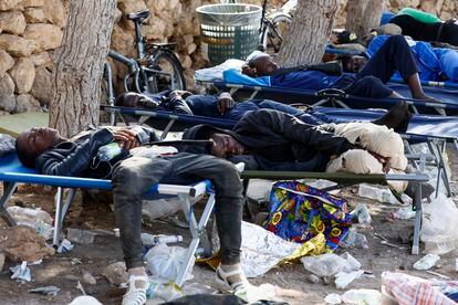 Varias personas descansan en tumbonas colocadas fuera del centro de acogida en la isla italiana de Lampedusa, este viernes.