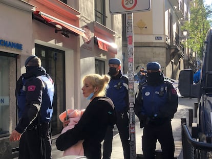 Una mujer con su bebé, rodeada de agentes de policía, frente al antiguo palacio de la Infanta Carlota, en Madrid.