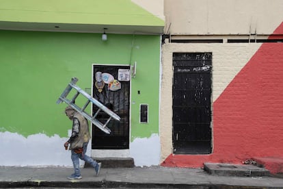 Un pintor de casas camina con una escalera mientras trabaja en las fachadas de la viviendas del cerro San Cristóbal, el 18 de Agosto de 2021, en Lima.