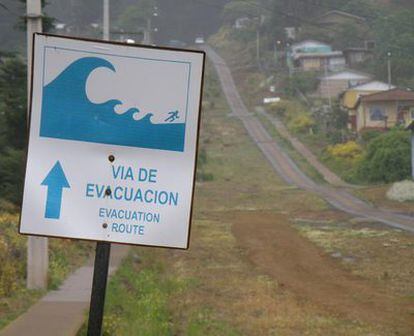 Cartel que indica la vía de evacuación en caso de maremotos, conocida como "la polvora", en la isla chilena Robinson Crusoe. El camino que se ve al fondo era la única huída posible para los vecinos de San Juan Bautista del 'tsunami' que asoló su municipio en la madrugada del pasado 27 de febrero.