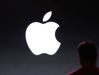 Una persona junto a un logo de Apple.