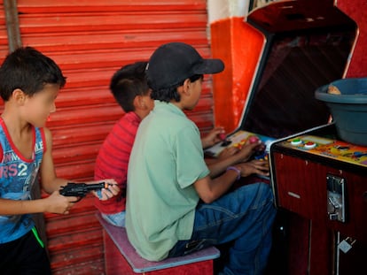 Imagen de archivo de un niño jugando con una pistola de juguete detrás de sus amigos que se entretienen en unas maquinitas.