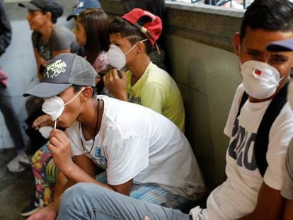 Gente con mascarillas cerca de una parada de metro en Caracas.
