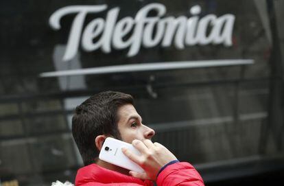 Un hombre habla con su m&oacute;vil, ante la sede de Telef&oacute;nica en Madrid.