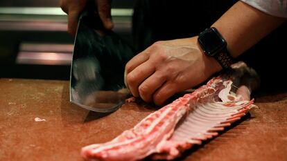 Un carnicero prepara chuletas en el mercado de Chamartín de Madrid.