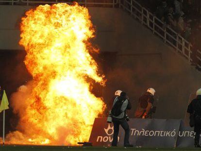 Varios polic&iacute;as intentan extinguir un incendio causado por los hinchas del Panathinaikos.